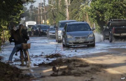 FILE - In this Feb. 10, 2019 file photo, vehicles pass through surf that washed over a roadway on Oahu's north shore near Haleiwa, Hawaii. (Cindy Ellen Russel/Honolulu Star-Advertiser via AP, file)